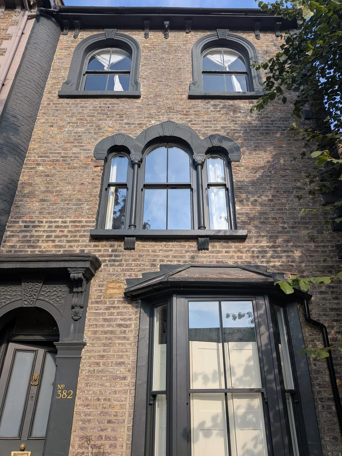 Accoya sash windows in Hackney E8 — the finished ground-floor bay and arched windows above on a Victorian terrace