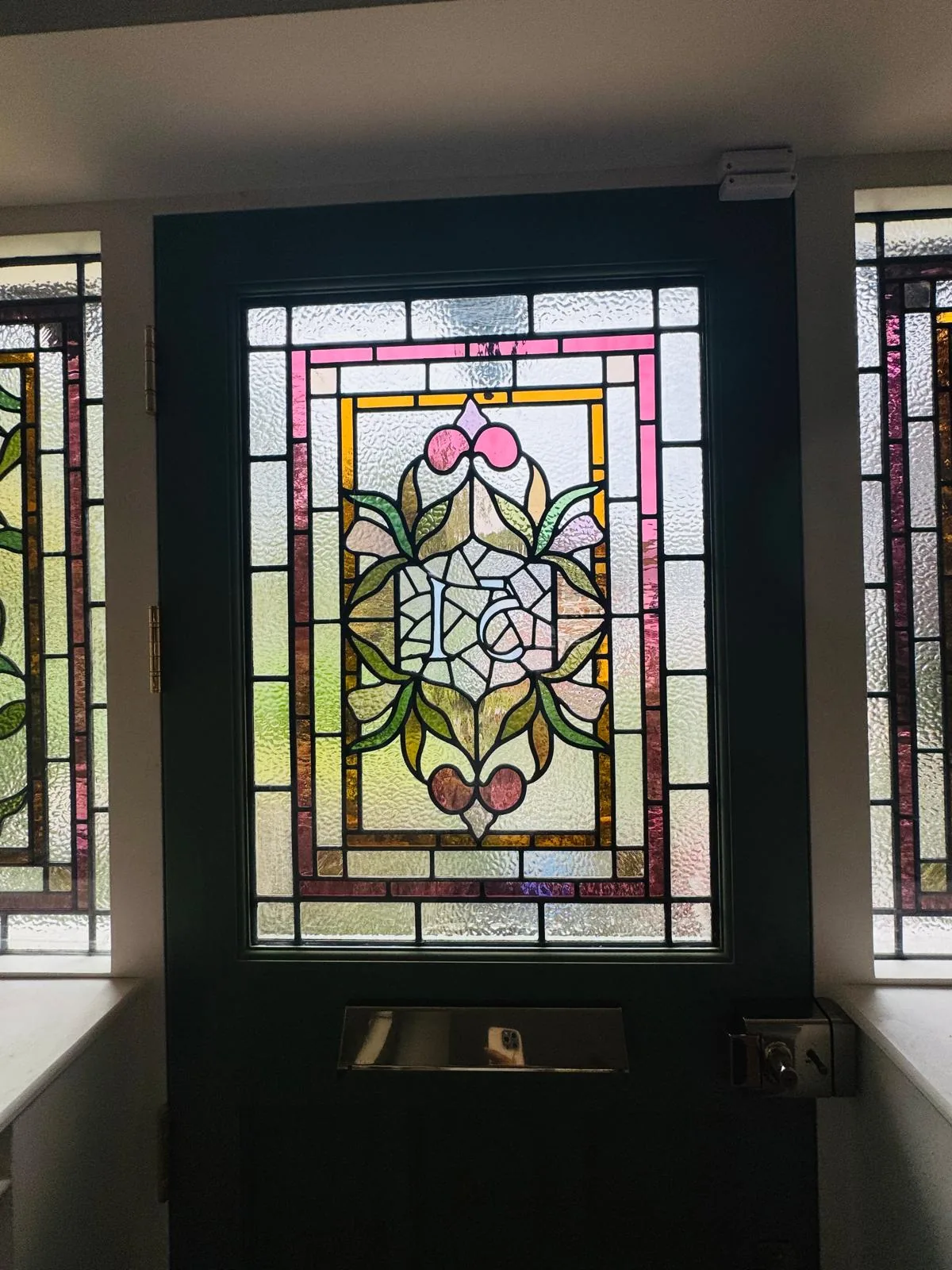 Close-up of the bespoke stained glass door panel showing the central floral motif and leadwork