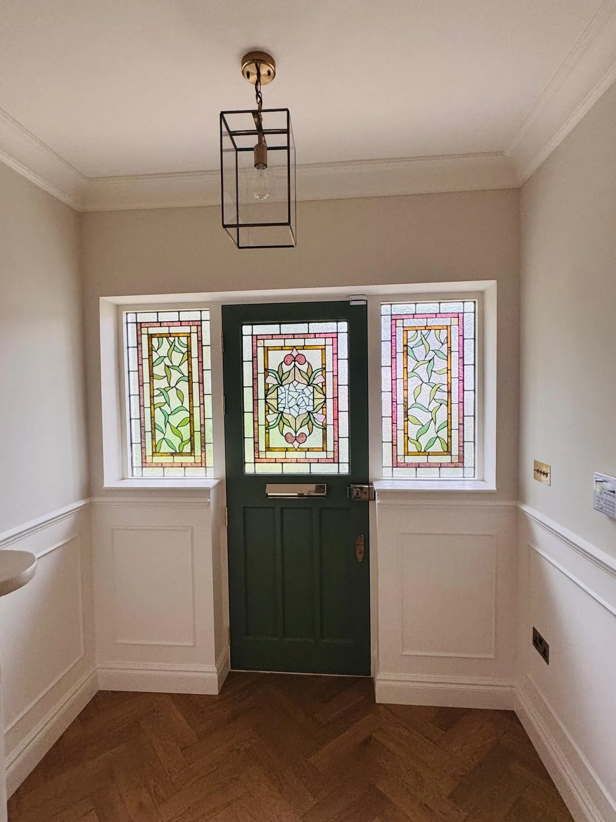 The same entrance seen from inside the hallway, with stained glass door and side windows