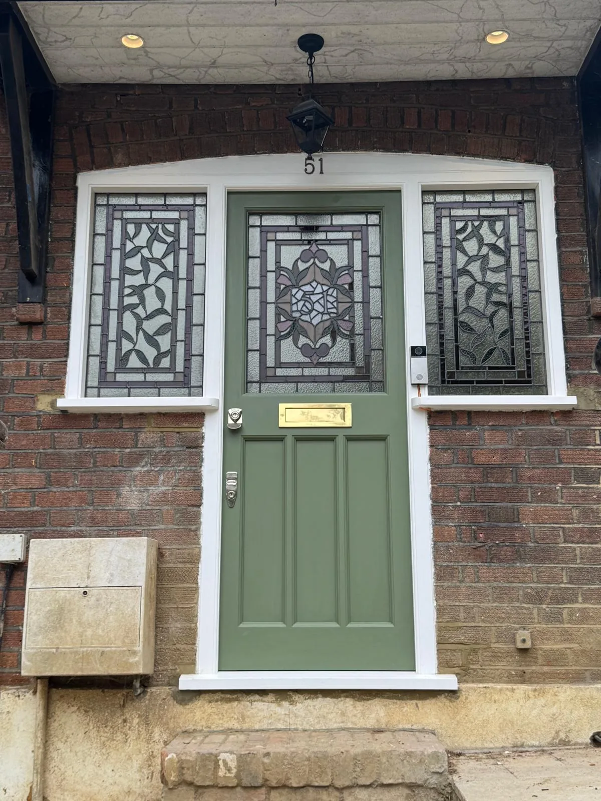 Sage-green Accoya front door with bespoke stained glass, viewed from the porch