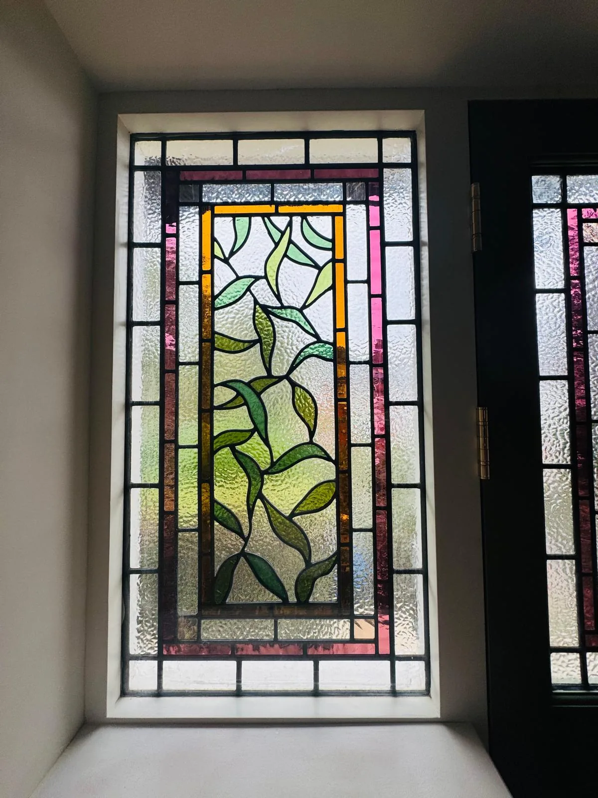 Close-up of a stained glass side window with trailing botanical leaf design in textured glass