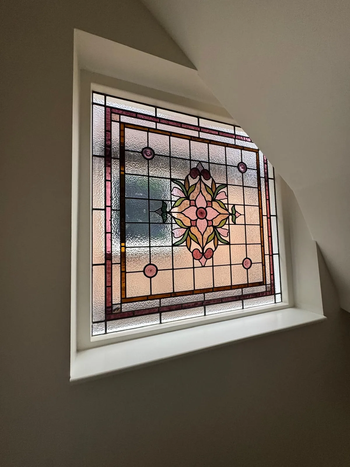 The staircase stained glass window lit from behind, showing warm coloured light in the stairwell