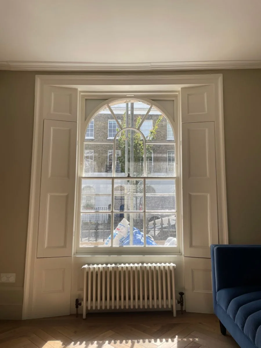 Panelled box shutters either side of an arched sash window