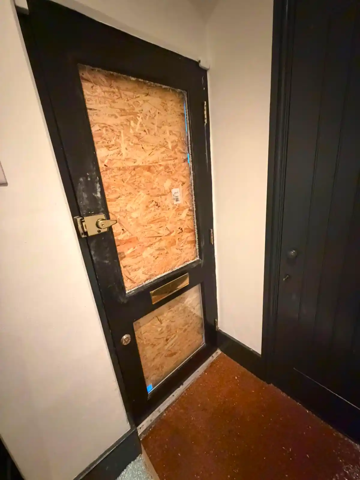 Secure temporary boarding fitted to a London front door to make the property safe while replacement glass is sourced