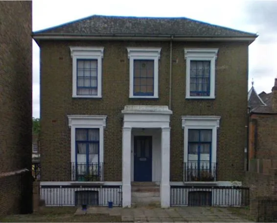 The client's reference photograph showing the property's original blue-painted timber windows on the front elevation