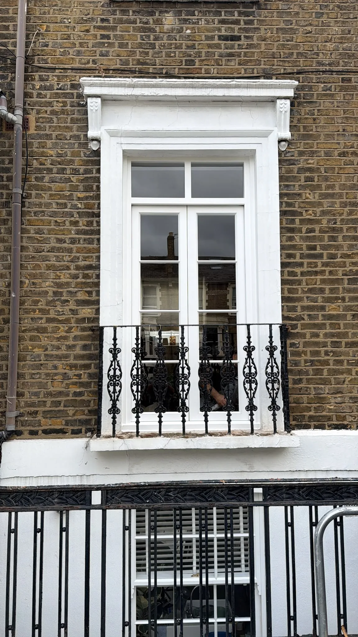New timber French doors with fanlight above, seen from the street behind the original cast iron balcony