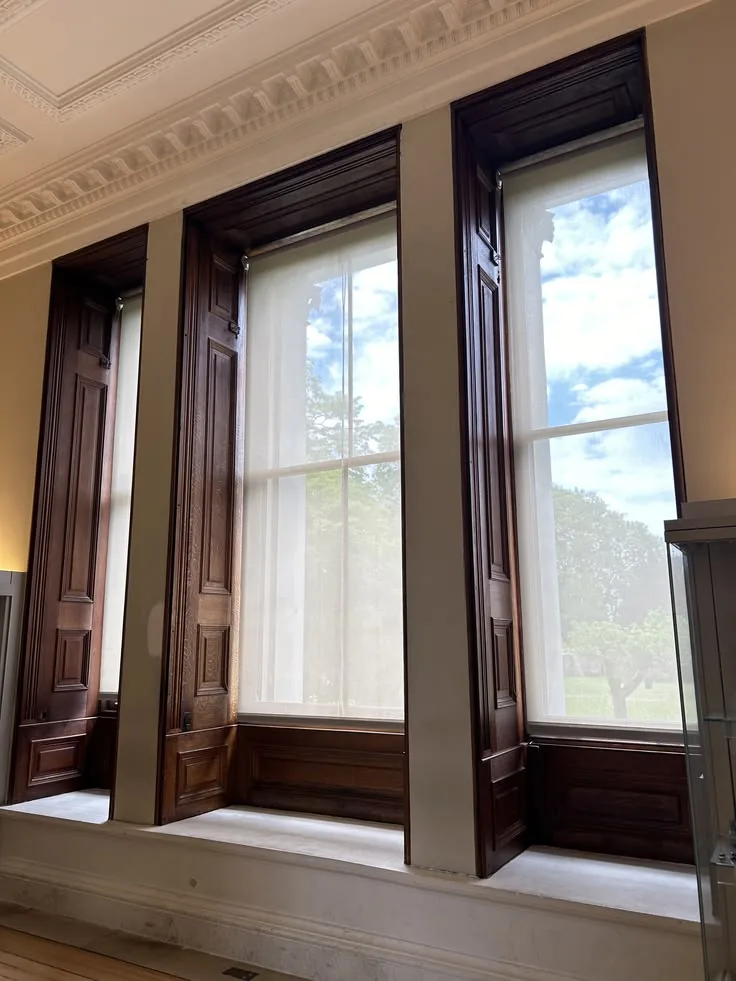 Dark oak panelled box shutters beside tall sash windows