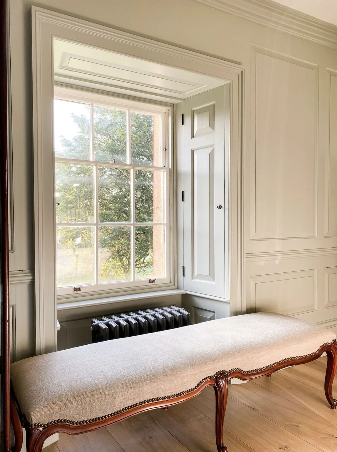 Raised and fielded panelled shutters in a deep window reveal beside a sash window