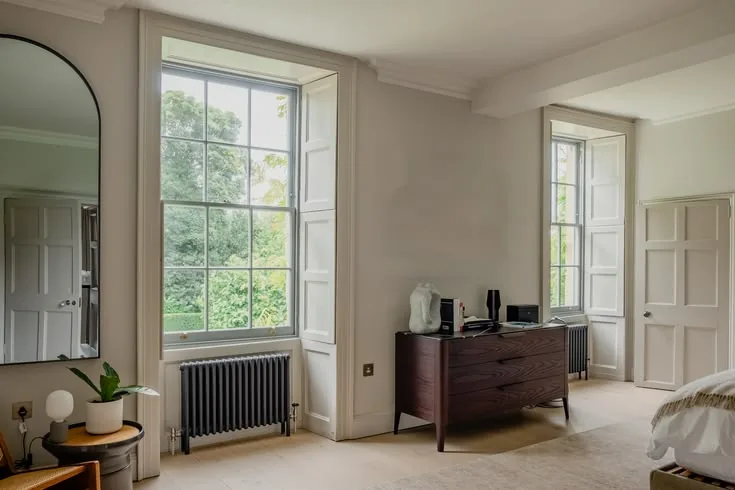 Folding box shutters beside Georgian-style sash windows in a bedroom