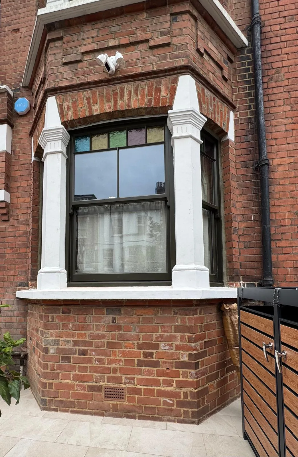Completed Accoya sash windows in the Islington bay, finished in dark olive bronze with the original stained glass margin lights retained