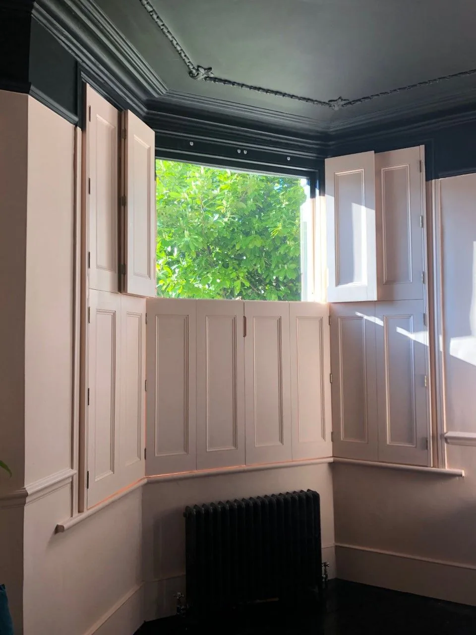 Tier-on-tier timber shutters fitted across a bay window