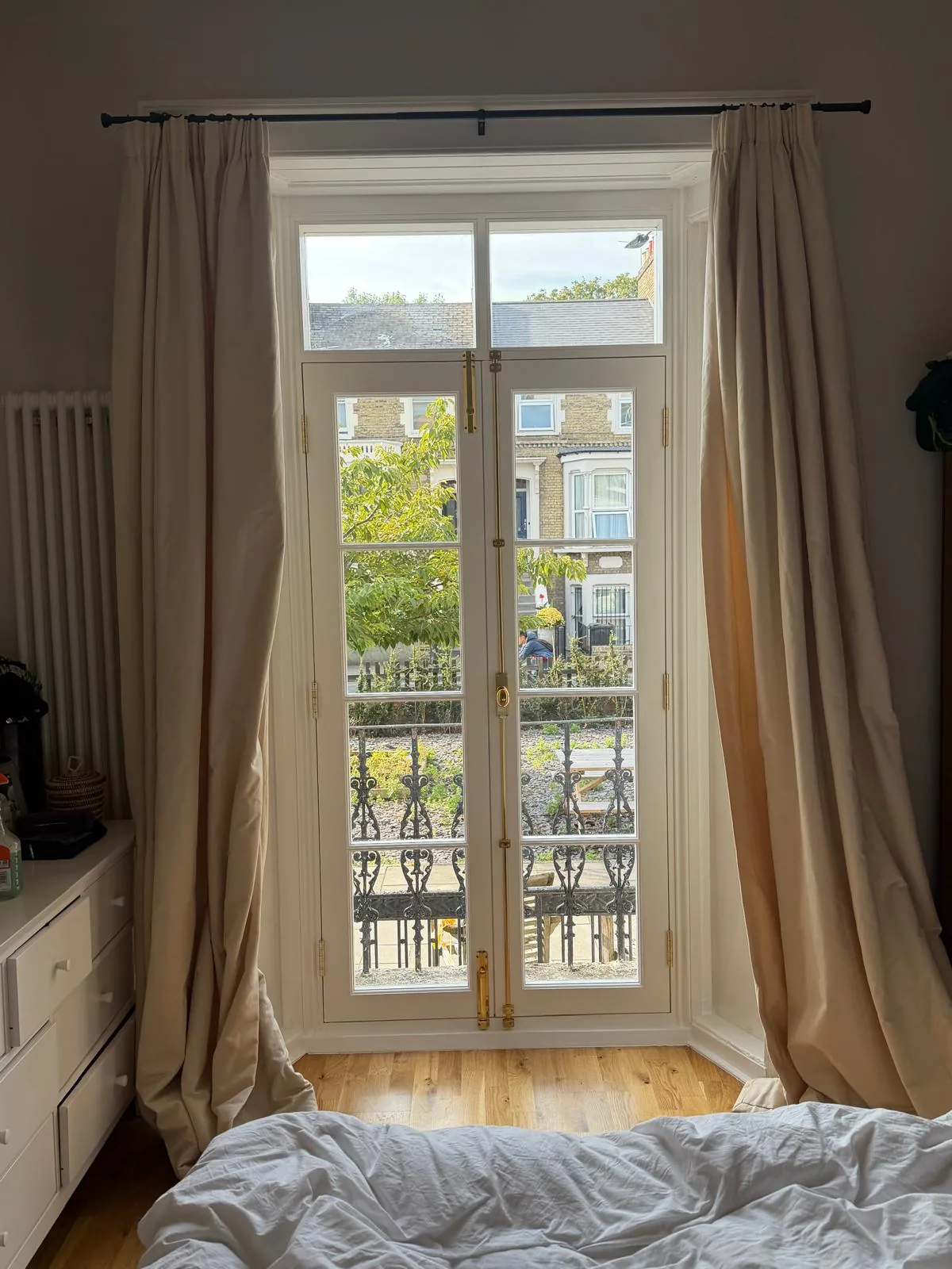 Timber French doors seen from inside a bedroom, with brass espagnolette bolt and fanlight above