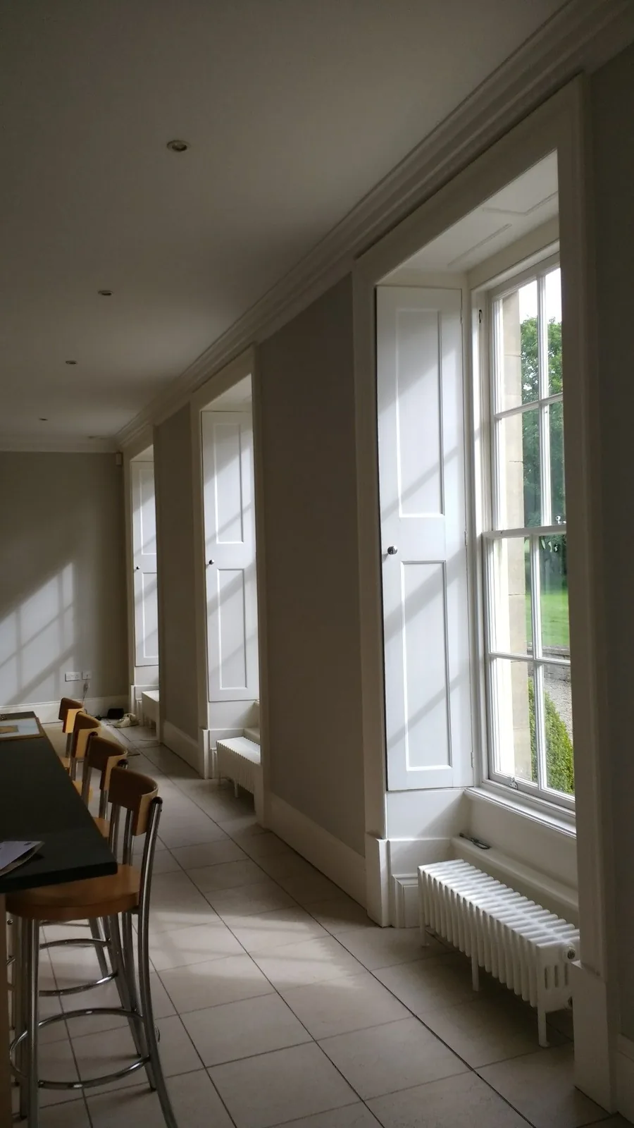 Traditional panelled box shutters folded into deep reveals along a run of sash windows